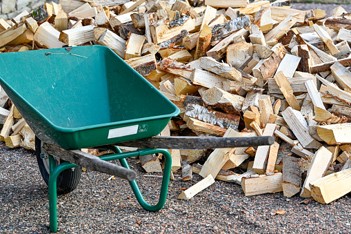 pile of firewood and green wheelbarrow for transportation Sweden january 2022