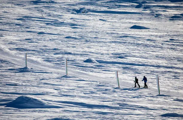 Photo of Back country skiers' silhouettes moving up in winter mountain