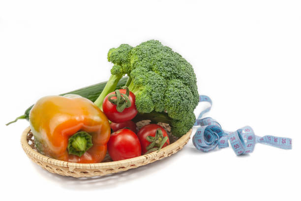 Fresh broccoli, cucumber, pepper and tomatoes on a wicker basket on white background. Healthy food concept. Vegetarianism and veganism