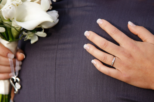 Bride's hands hugging groom showing wedding ring and bouquet