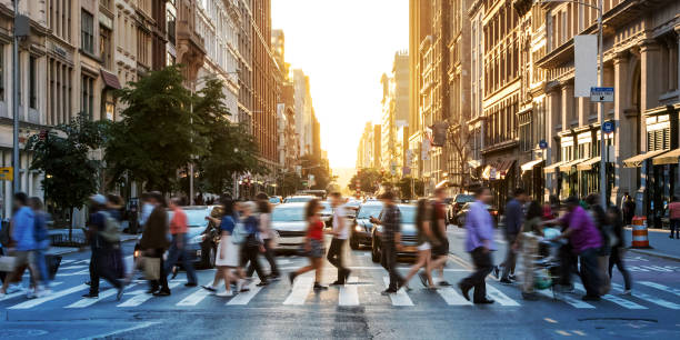 folle di persone che camminano attraverso un attraversamento pedonale trafficato all'incrocio tra la 23rd street e la 5th avenue a manhattan new york city - camminare foto e immagini stock