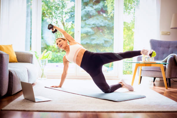 istock Shot of a middle aged woman using a laptop while exercising at home 1367852339