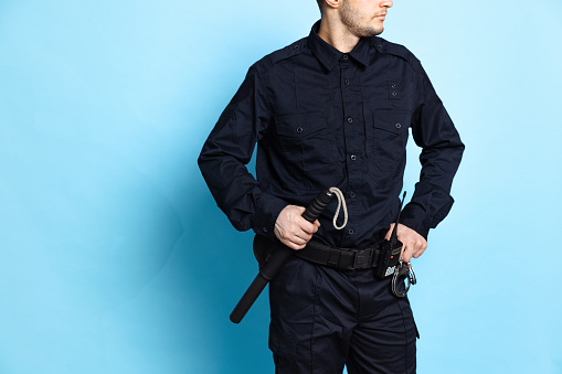 Cropped image of male policeman officer wearing black uniform with professional ammunition isolated on blue background. Concept of job, caree, safety. Security service. Copy space for ad