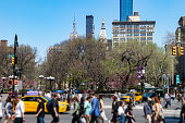 Diverse crowd of people walking through a busy intersection on 14th Street at Union Square Park in New York City