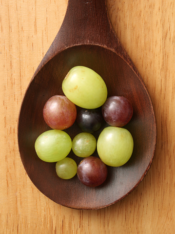 Top view of wooden spoon with varieties of grapes on it