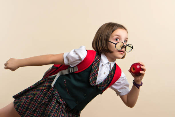 Portrait of her she nice attractive cheerful cheery smart clever pre-teen, girl holding in hand fresh apple having fun isolated over bright vivid shine orange background