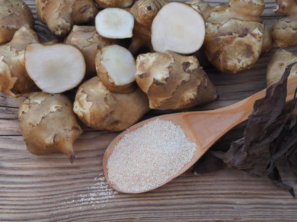 fruits of the jerusalem artichoke plant and natural powder with inulin on wooden table,closeup. healthy helianthus tuberosus root vegetables and dietary supplement for diabetes prevention and treatment - diabetes superfoods imagens e fotografias de stock