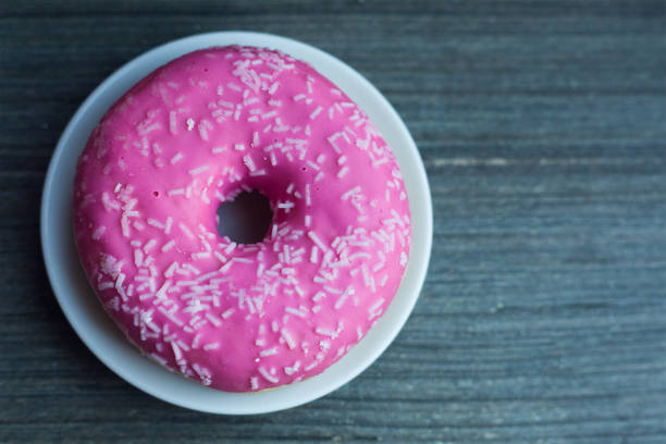 istock Purple doughnut with coconut on white round plate put on left side on wooden grey table 1367856387