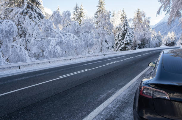 statyczne ujęcie solidnego czarnego silnika tesla model 3 z podwójnym silnikiem dalekiego zasięgu z przyciemnianymi szybami i aerodynamicznymi kołami z ośnieżoną górą w słoneczny dzień w zimie - sunny day mountain mountain range winter zdjęcia i obrazy z banku zdjęć