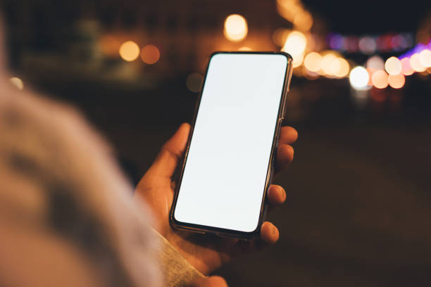 istock Smartphone with blank display in female hand against lights 1367858794