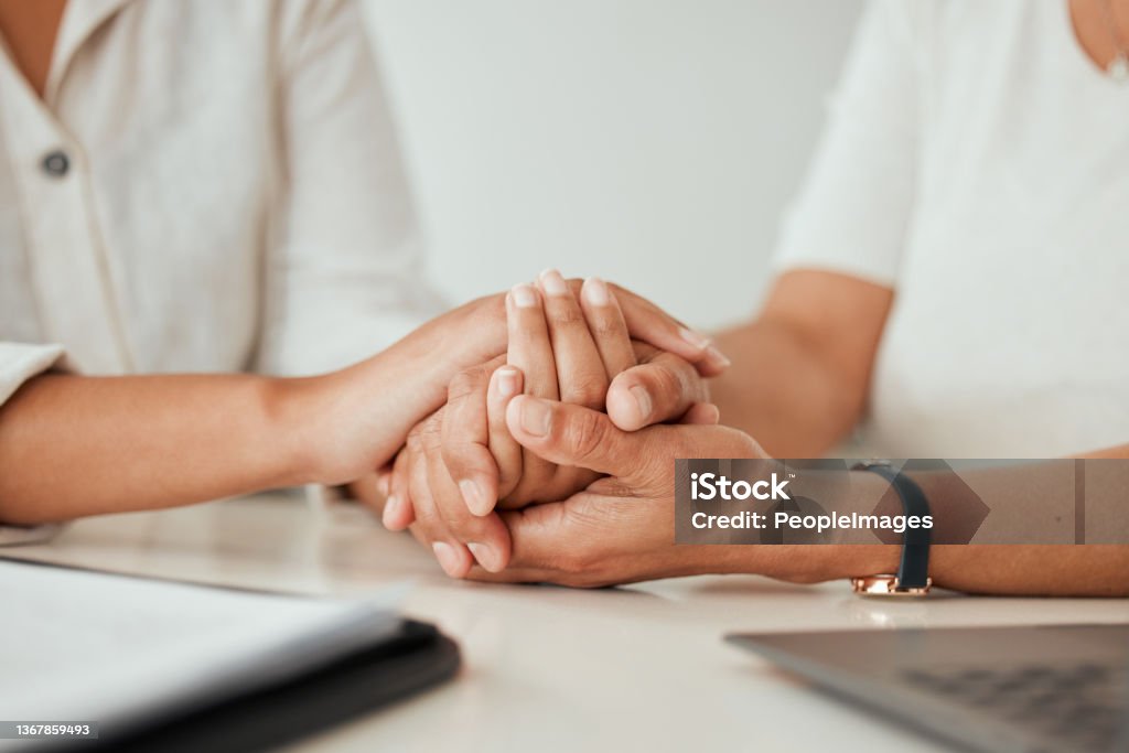 Shot of two unrecongizable women holding hands while sitting at the kitchen counter If you can't run, we will walk together Trust Stock Photo