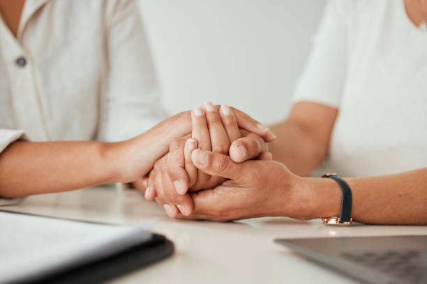 shot of two unrecongizable women holding hands while sitting at the kitchen counter - confiança imagens e fotografias de stock