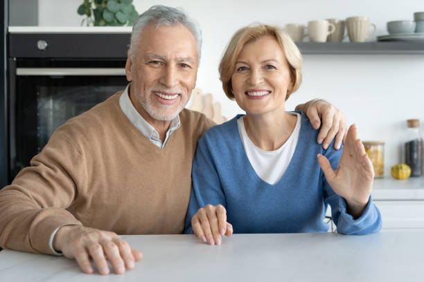 istock Smiling senior couple looking at camera when sitting at table 1367863164