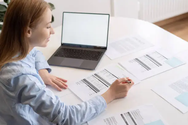 Photo of Stylish dressed woman examining variety of documents laying on table