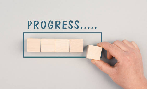 istock The words progress is standing over the loading bar, hand puts last cube to the upload, gray colored background 1367863971