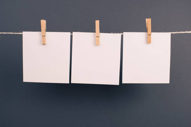 istock Empty white sheets of paper in a row hanging on a string, copy space for pictures and text, message communication and marketing background, gray color 1367863982