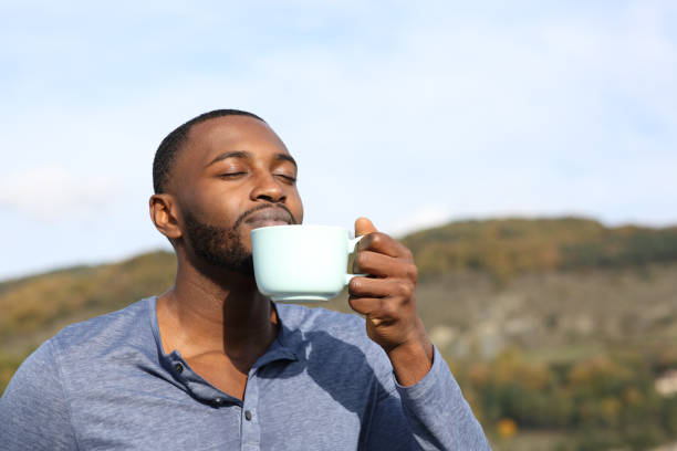 Man with black skin drinking and smelling coffee stock photo