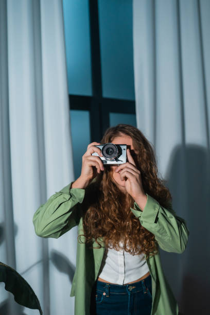 istock Cheerful young woman making photo on camera at home 1367865747