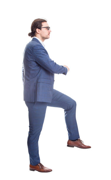 istock Side view confident businessman climbing a imaginative staircase isolated on white background. Concept of career development and goal achievement. Full length business person makes a big step 1367865997