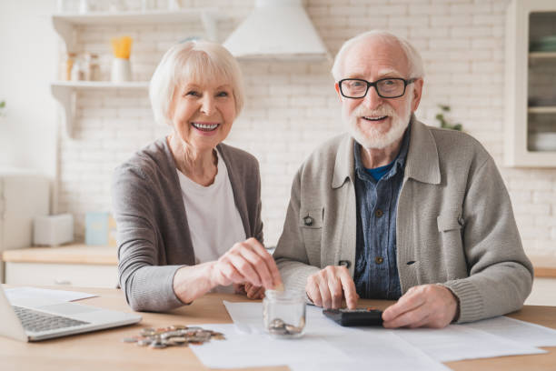 concept d’épargne. œuf au nid de vieux vieux couples âgés grands-parents mari et femme économiser de l’argent, économiser la pension, prêt hypothécaire à la maison en utilisant un ordinateur portable et mettre des pièces de monnaie dans la bo - senior couple senior adult pension couple photos et images de collection