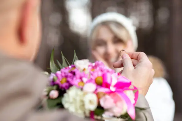 Photo of Portrait of two people couple smiling happy woman and man proposal holding bouquet of flowers together outdoors blur