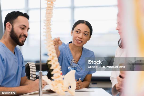 Female Medical Student Asks Teacher Question While Male Friend Listens Stock Photo - Download Image Now