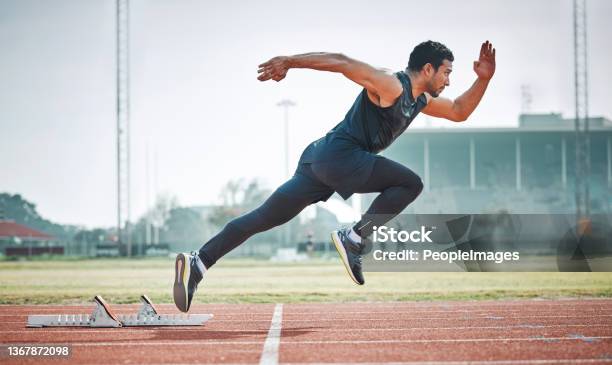 Full Length Shot Of A Handsome Young Male Athlete Running On An Outdoor Track Stock Photo - Download Image Now