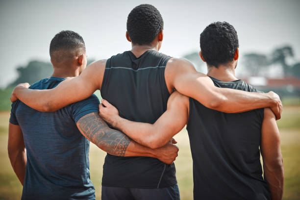 Rearview shot of three unrecognizable young male athletes standing together on an outdoor running track Their dreams are in sight arm around stock pictures, royalty-free photos & images