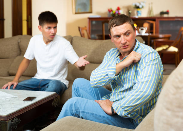 istock Upset father sitting while quarreling with his teenage son 1367873155