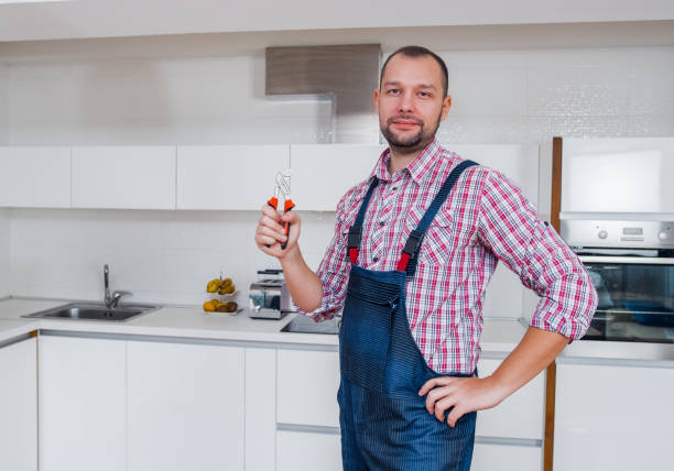 istock Handsome workman in uniform with a pliers standing in the kitchen 1367873754