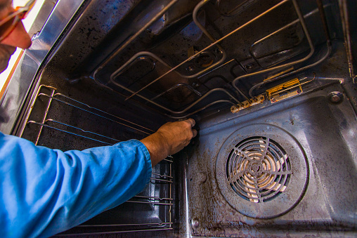 Old handyman fixing the motor fan in the oven