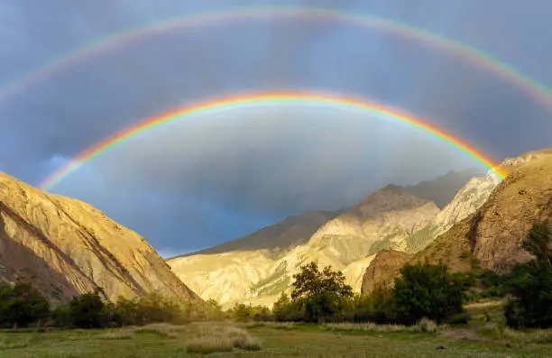 Photo of Rare double rainbow in the dark sky in the mountains.