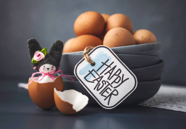 istock Stack of bowls filled with organic brown eggs next to a handmade bunny in an eggshell. Easter background with message. 1367877584