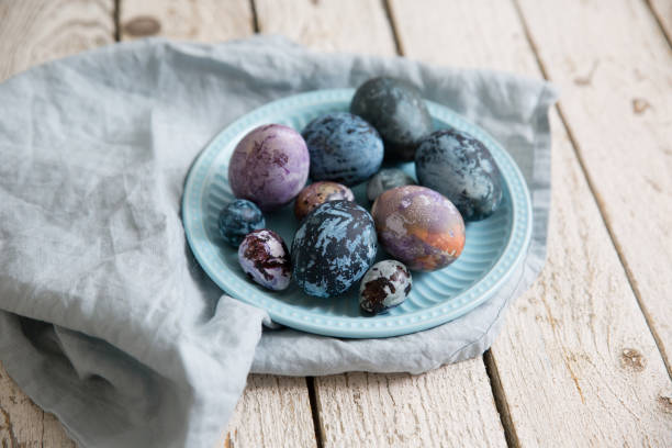 istock Painted Easter eggs with a marble pattern in blue, purple colors. In a blue plate on a wooden white table. 1367881549