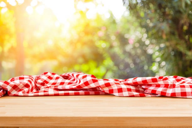istock Table with crumpled picnic blanket and nature background 1367883477