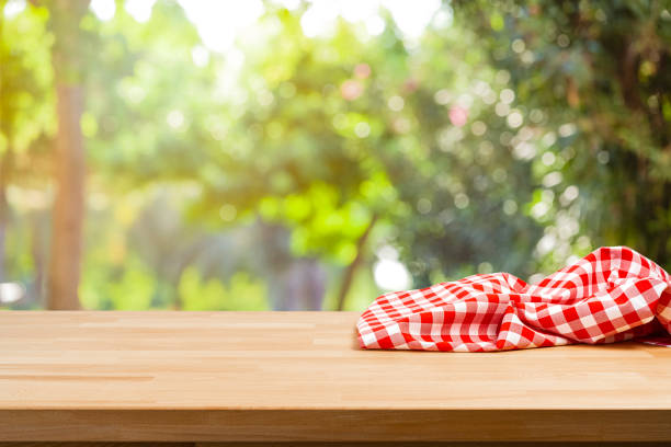 istock Empty table with crumpled picnic blanket and nature background 1367883486
