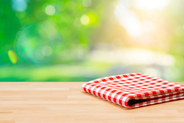 istock Table with folded picnic blanket and lush foliage background 1367883503