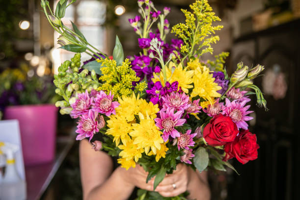 Local florist creating mixed flower bouquets for an client order.