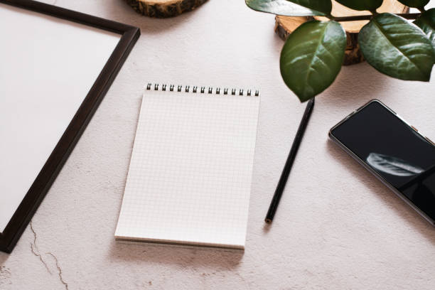 istock Eco desk. Open notepad, pencil and smartphone on a light concrete background. The concept of choosing means for writing. 1367884888