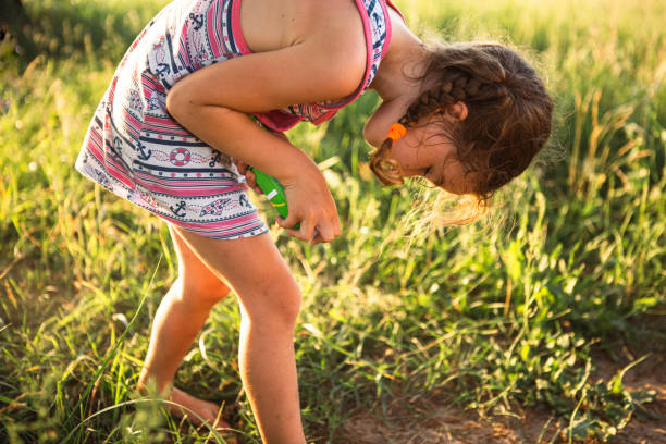 girl sprays mosquito spray on the skin in nature that bite her hands and feet. protection from insect bites, repellent safe for children. outdoor recreation, against allergies. summer time - mosquito child bug bite scratching imagens e fotografias de stock