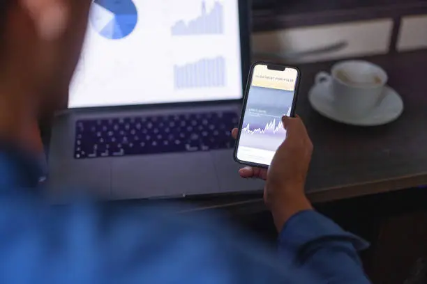 Photo of Close up shot of a man checking his investment portfolio on his phone