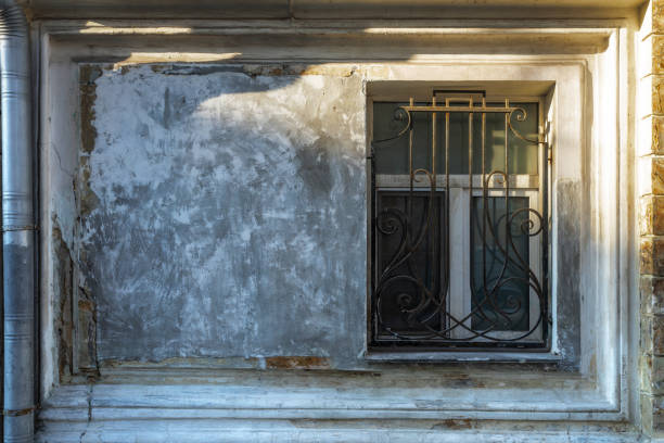 Old weathered wall and window with a metal grate