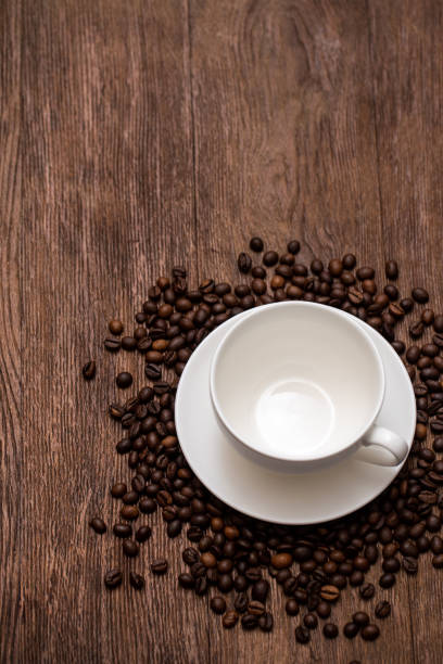 Empty coffee cup and roasted coffee beans on a wooden table.