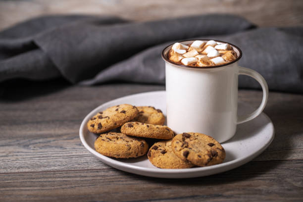 Chocolate chip cookies and coffee cup on a wooden table.