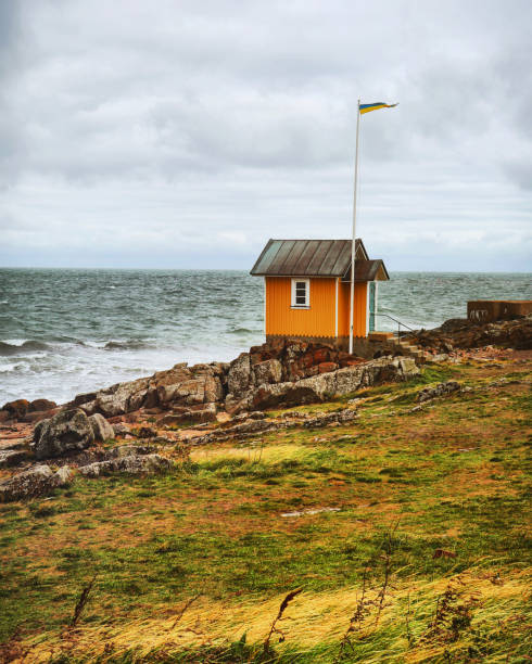 Small house, orange,no people , coastline, windy, cloudscape, scenic nature,rocks, grass