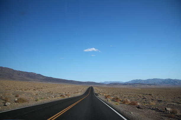 istock Straight road towards mountain range in horizon at Death Valley 1367893422