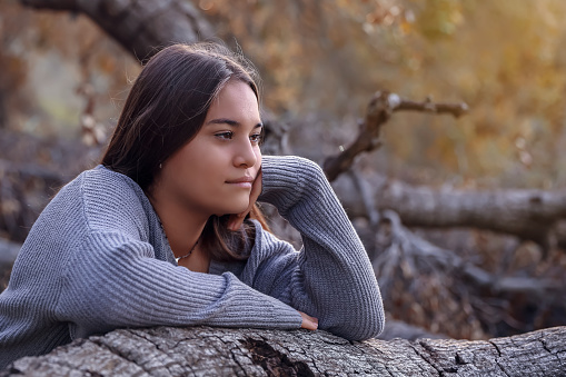 Hispanic teenager girl leaning on tree