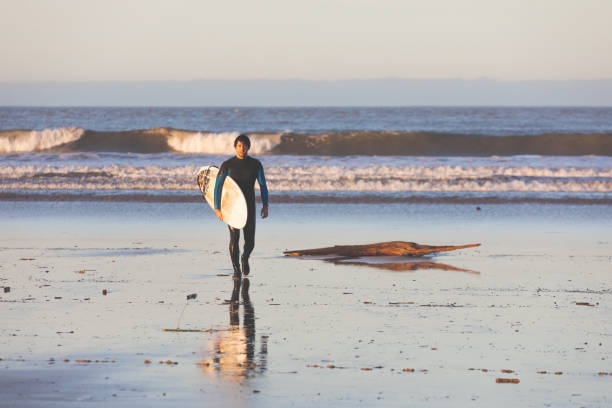 サーフボードを持ってビーチを歩く若い白人の男。 - oregon beach ストックフォトと画像