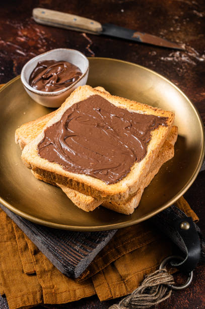 istock Stack of Toasts with chocolate Hazelnut cream in plate. Dark background. Top view 1367895928