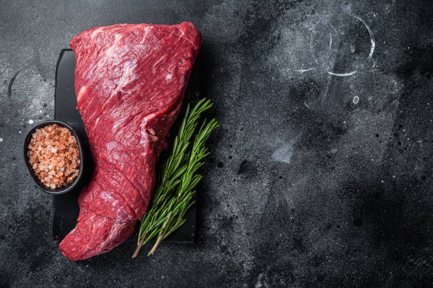 istock Raw American Tri Tip beef steak on marble board. Black background. Top view. Copy space 1367896249